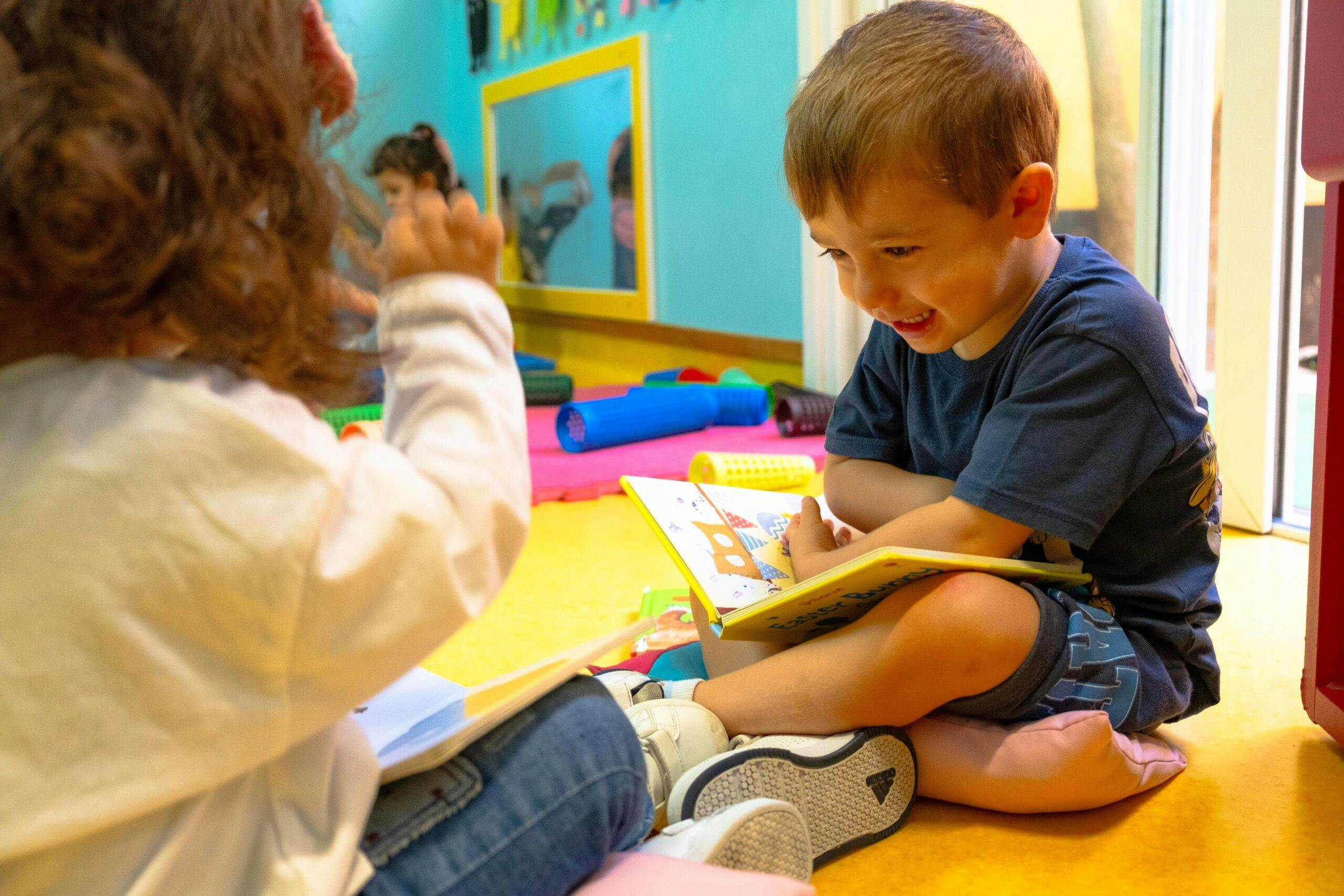 Duas crianças a lerem livros, na sala do infantário A Toca dos Traquinas