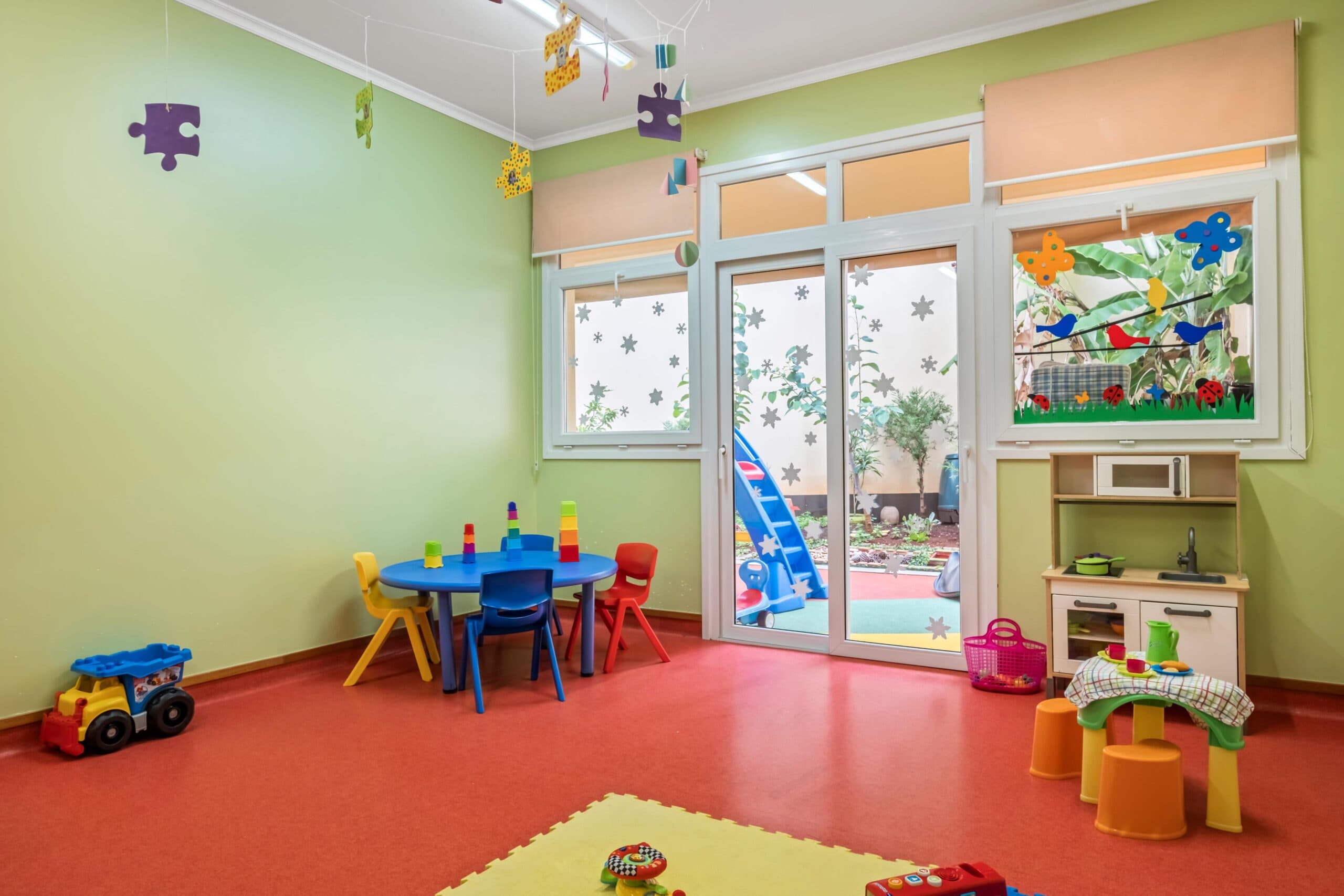 Sala transição Castores com mesas e cadeiras coloridas, e diversos brinquedos, no infantário A Toca dos Traquinas