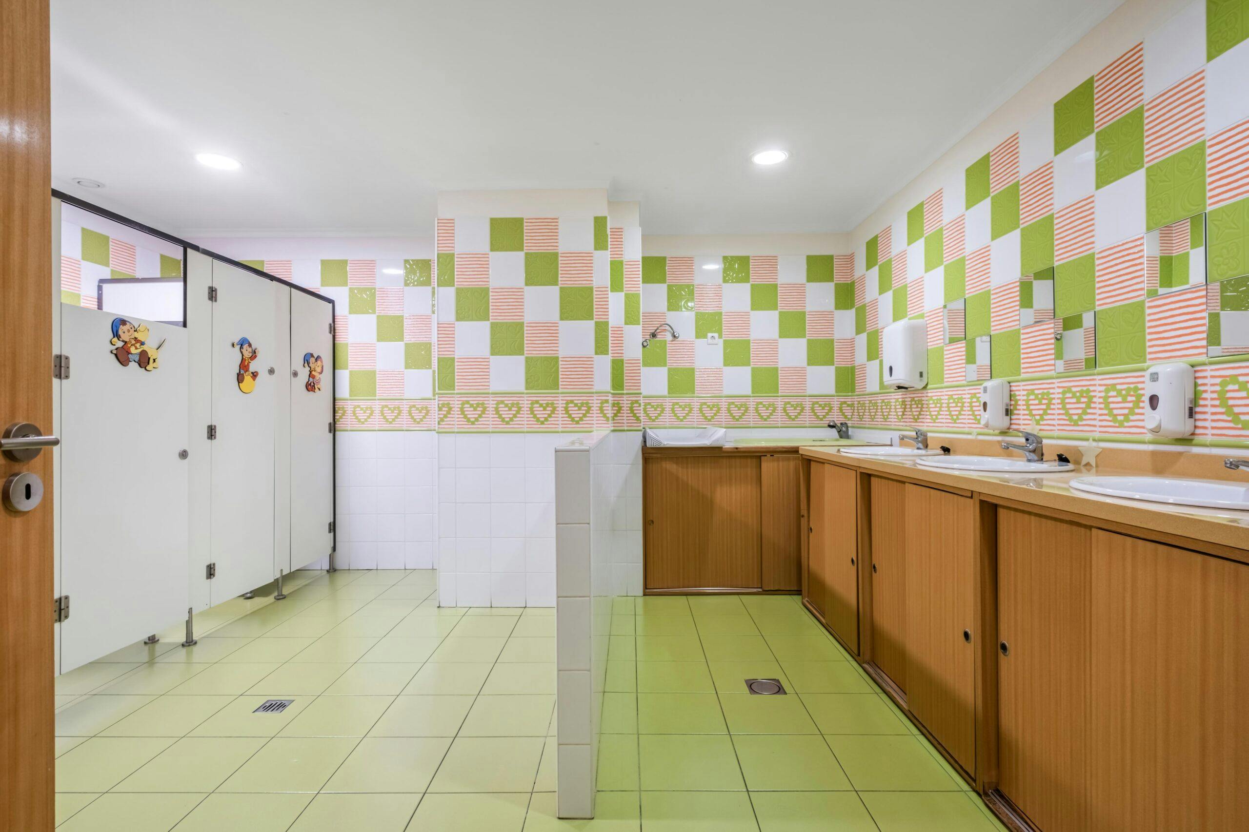 Casa de banho para crianças com azulejos verde e laranja no infantário A Toca dos Traquinas