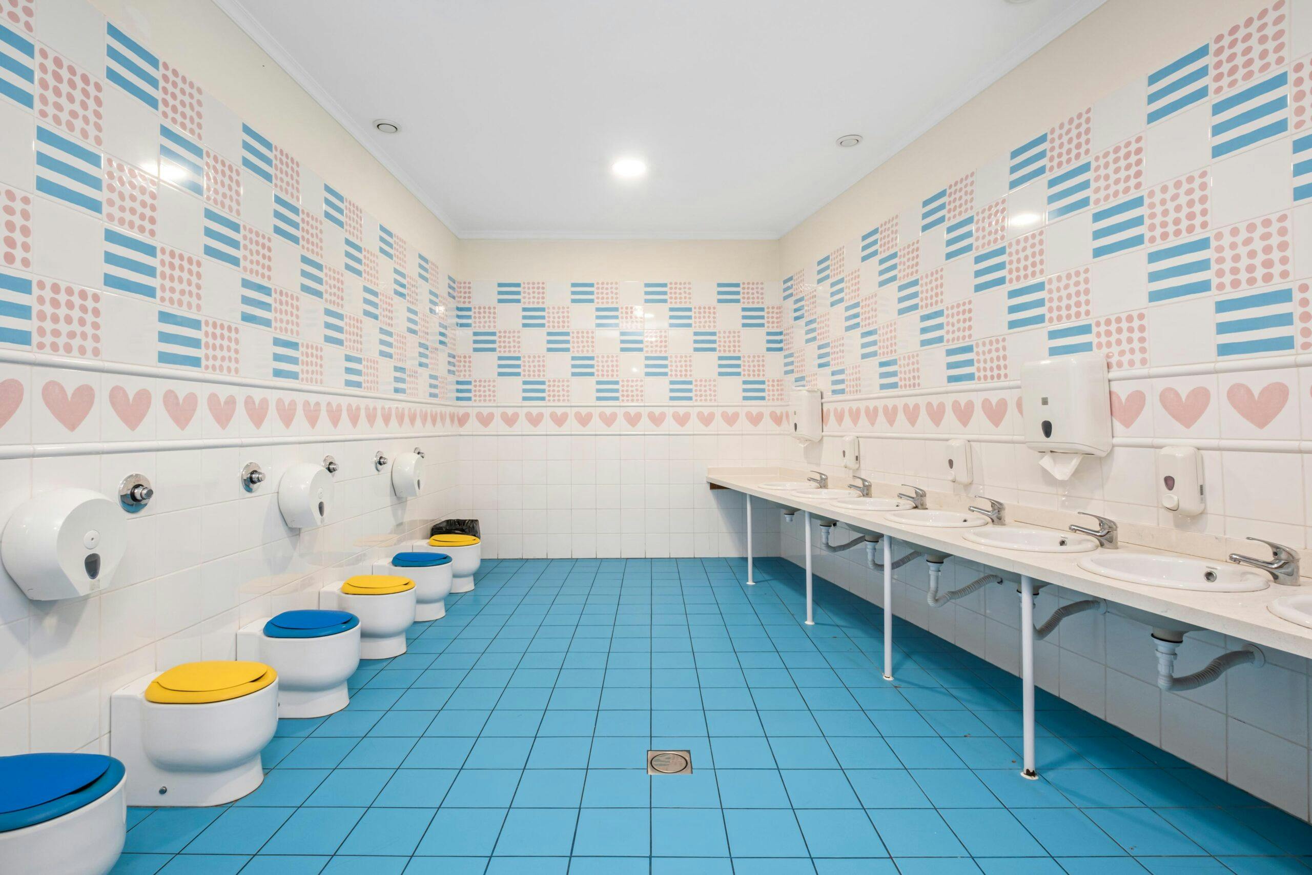 Casa de banho para crianças com azulejos rosa e azul no infantário A Toca dos Traquinas
